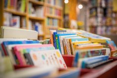 Bücherei Bunte Kinderbücher stehen in roten Kisten aufgereiht in einer Bücherei oder Buchhandlung. Im Hintergrund sind Bücherregale mit weiteren Büchern zu sehen.