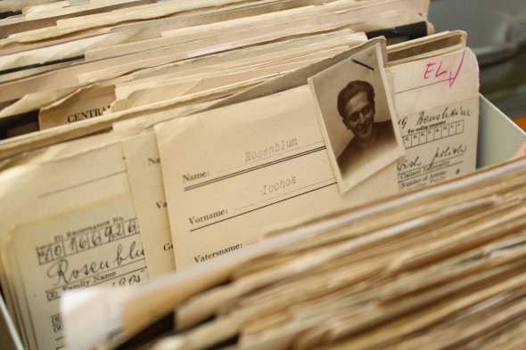 Karte aus dem Bestand der Displaced Persons (DPs) mit Foto Eine Akte aus dem Archiv des Internationalen Suchdienstes (ITS) in Bad Arolsen, die aufgeschlagene Karteikarten mit persönlichen Informationen und ein schwarz-weißes Porträtfoto zeigt.