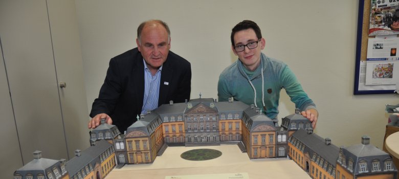 Schlossmodell Wilhelm Müller und Tobias Rückschloss vom Fachbereich Touristikservice und Kultur sitzen hinter dem Schlossmodell