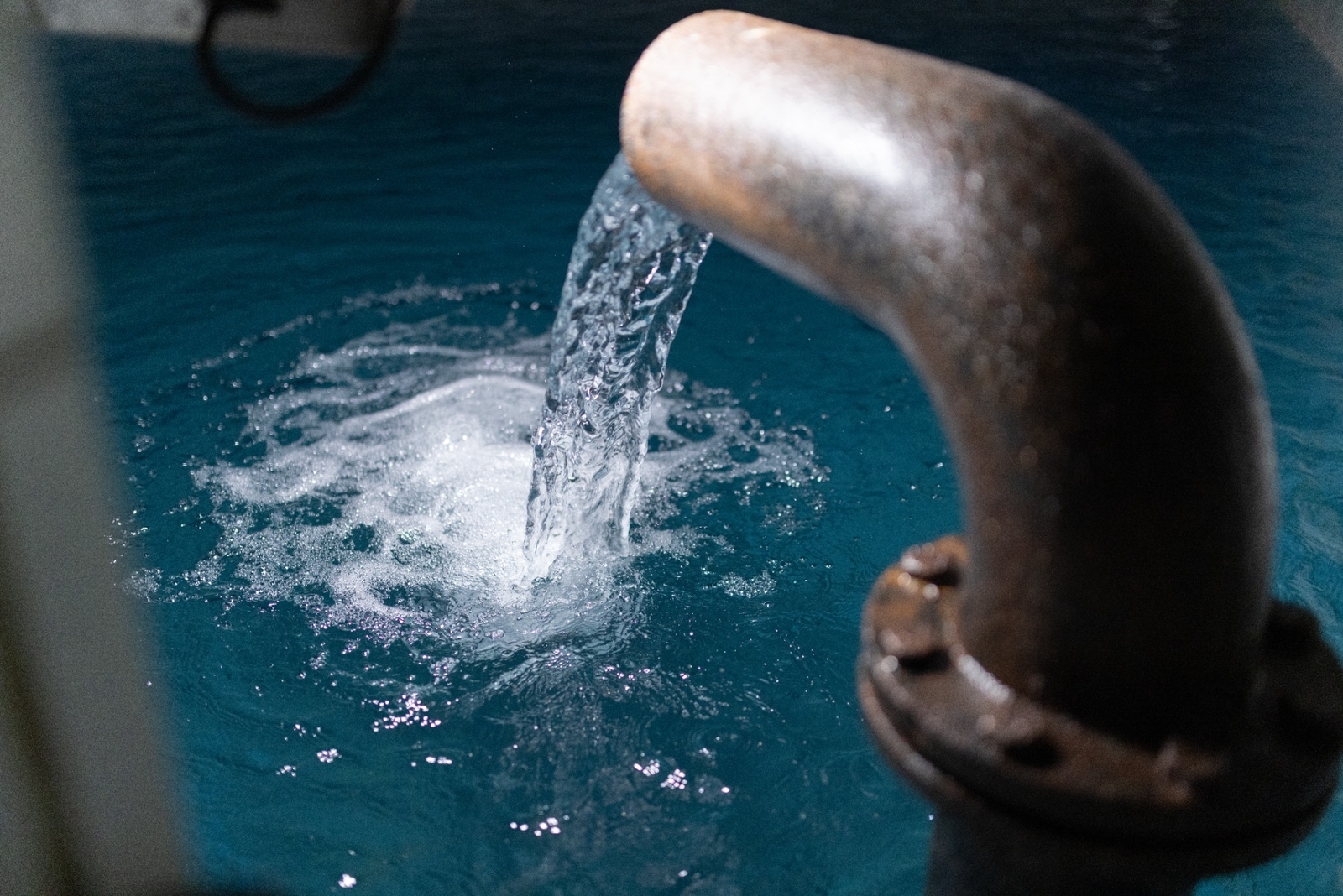 Wasser läuft aus einem Hahn in ein großes Becken