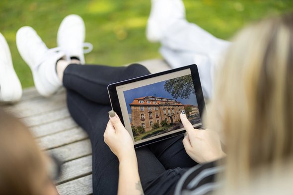 jemand sitzt auf einer Bank und bedient ein Tablet