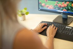 Büro Arbeitsplatz Eine Mitarbeiterin sitzt am Schreibtisch in ihrem Büro und tippt etwas auf der Tastatur.