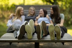 Schuhe drei Personen sitzen auf einer Entspannungsbank nur die Schuhe sind im Vordergrund scharf gestellt