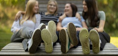 Schuhe drei Personen sitzen auf einer Entspannungsbank nur die Schuhe sind im Vordergrund scharf gestellt