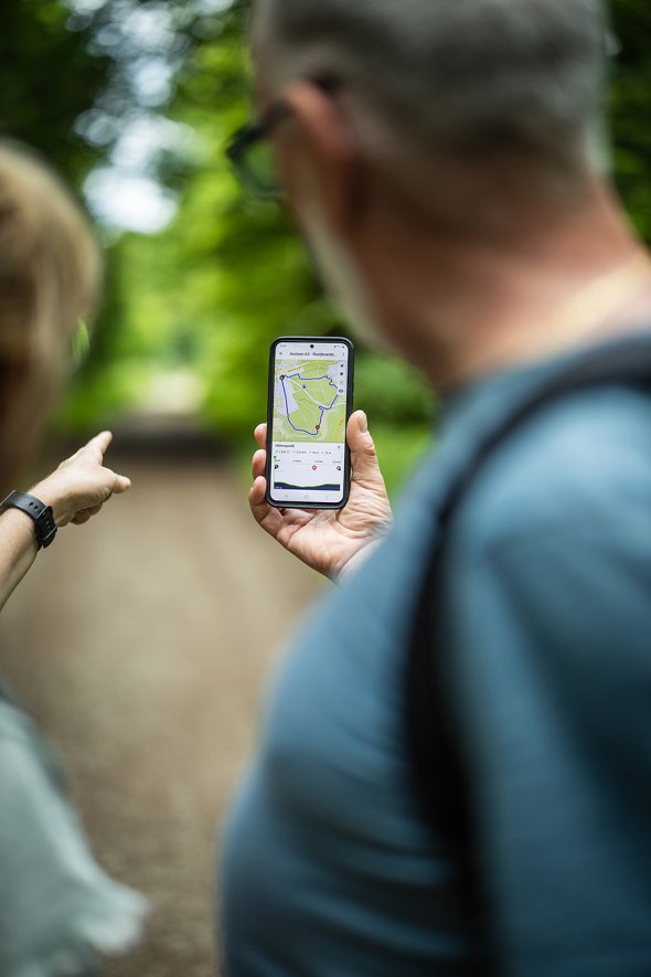 Personen sehen sich auf dem Smartphone eine Wanderroute an