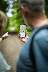 Personen sehen sich auf dem Smartphone eine Wanderroute an
